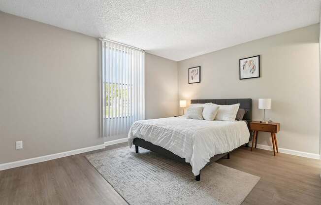 A bedroom with a bed, nightstand, and window.