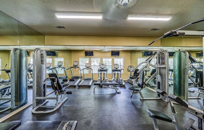 a gym with cardio equipment and weights on the floor