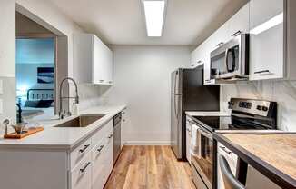 Kirkland WA Apartments for Rent - Woodlake - Modern Kitchen with White Cabinets, Stainless Steel Appliances, and Wood Flooring
