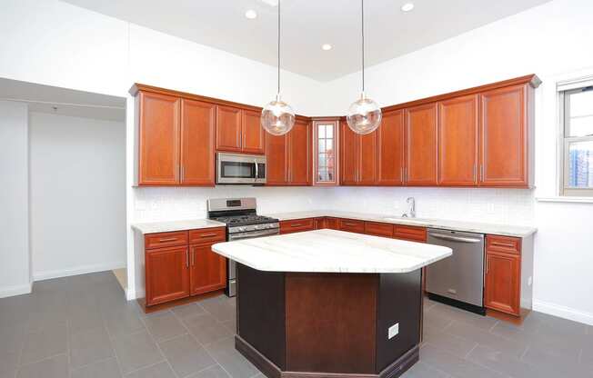 York House penthouse kitchen with maple cabinets, stainless steel appliances, granite countertops, pendant lighting and large island at York House, Saint Louis