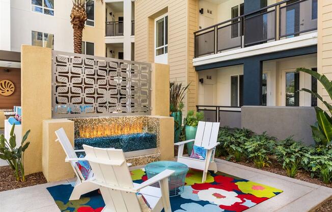 a patio with two chairs and a fire place in front of an apartment building