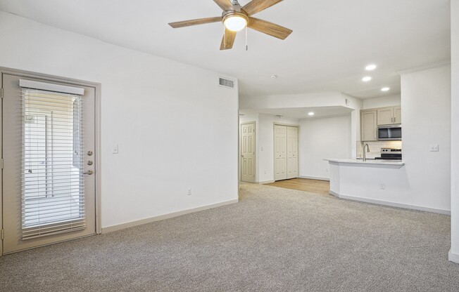 an empty living room with a ceiling fan and a kitchen at The Legends at Eagle Mountain Lake, Fort Worth, TX