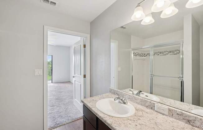 A bathroom with a sink, mirror, and lighting fixture.