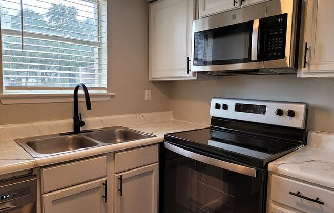 a kitchen with a sink and a stove and a microwave at Ivy Plains at Brooks Apartments, San Antonio , TX, 78223