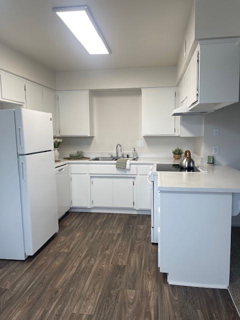 an empty kitchen with white cabinets and a refrigerator