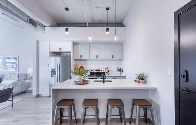A modern kitchen with a white island and bar stools.