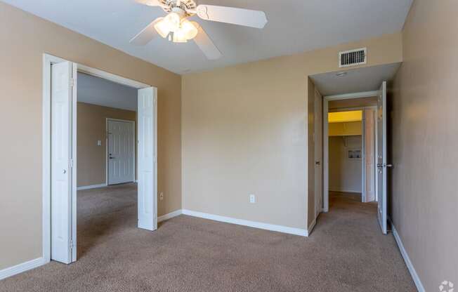 an empty living room with a ceiling fan