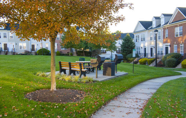 a park with a bench and a tree in front of houses