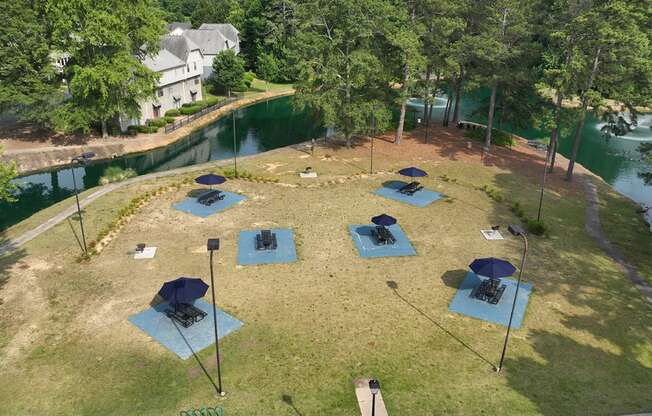 an aerial view of a campsite with blue mats and umbrellas on a grassy