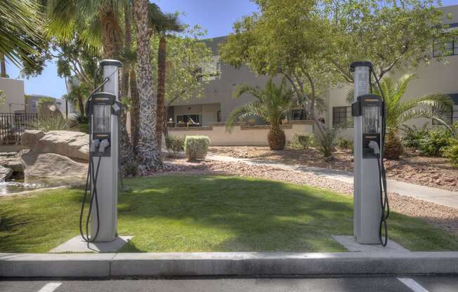 two gas pumps in a parking lot in front of a house at Vaseo Apartments, Phoenix, 85022