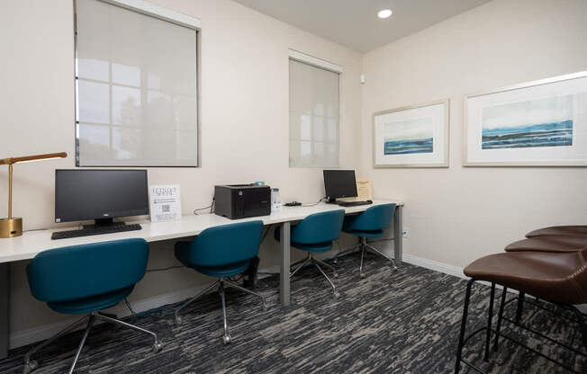 A room with a desk, chairs, and computers.