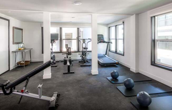 A spacious gym with a variety of equipment including a treadmill, a rowing machine, and a bench press.