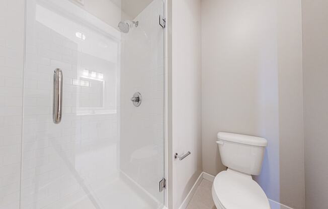 a bathroom with toilet and standing shower with glass door