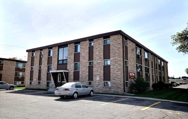 a brick apartment building with a car parked outside. Fargo, ND North Manor Apartments