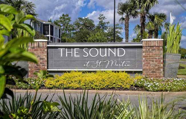 a sign for the sound in front of a building with palm trees