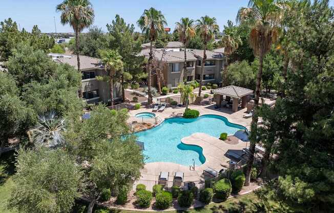 A swimming pool surrounded by palm trees and apartment buildings.