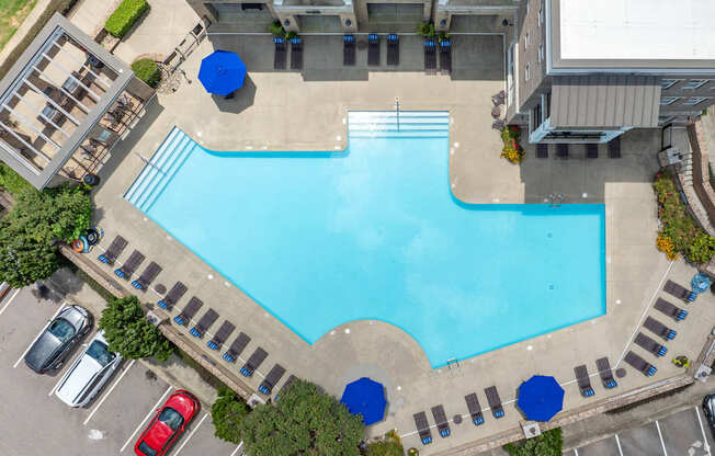 An aerial view of a swimming pool surrounded by a parking lot.