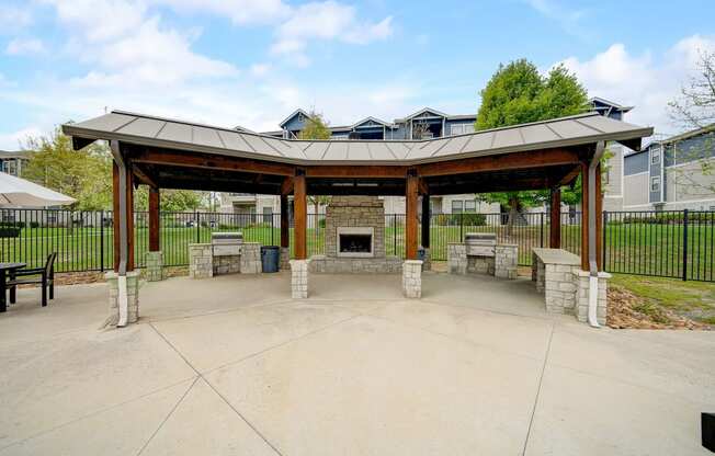 a covered patio with a stone fireplace and a pavilion