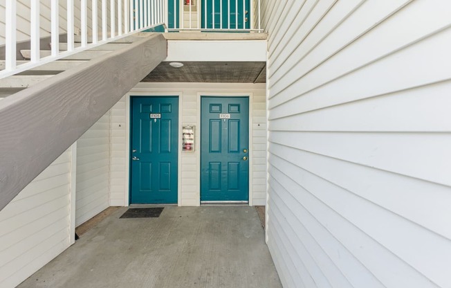 two blue doors on either side of a white house