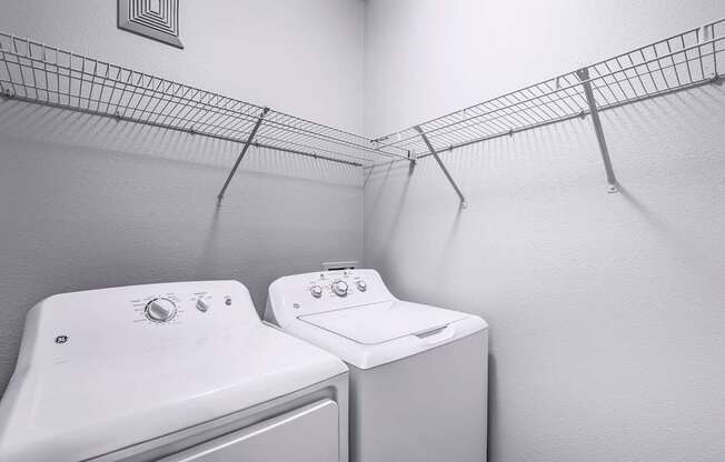 Two white washing machines in a laundry room.