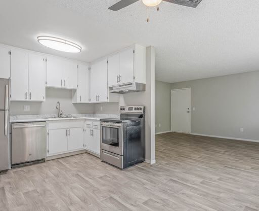 an empty kitchen with white cabinets and a ceiling fan at The Arches Apartments, El Cajon California