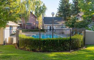 a swimming pool behind a wrought iron fence in a backyard