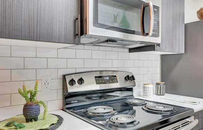 A modern kitchen with a stove top oven and a microwave above it.