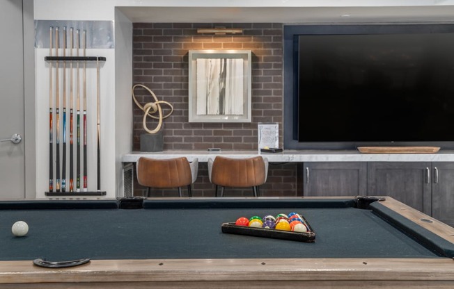 a pool table and a tv in a room with a brick wall