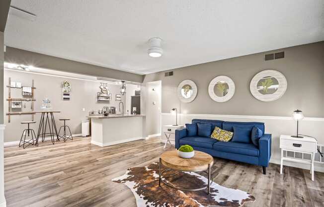 a living room with a blue couch and a coffee table in front of a kitchen with a at Beacon Hill and Great Oaks Apartments, Rockford, IL, 61109