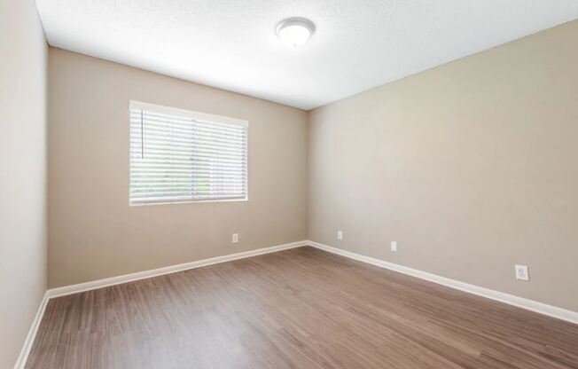 an empty living room with wood floors and a window