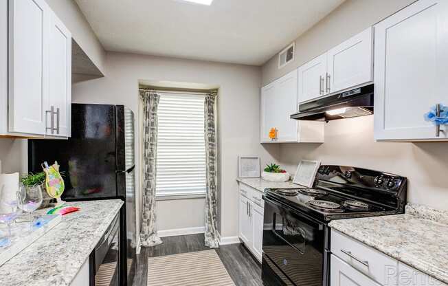 a kitchen with white cabinets and black appliances