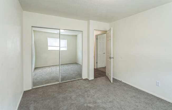 a bedroom with a carpeted floor and a mirrored closet