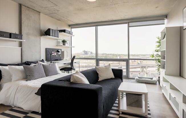 a living room with a black couch and a large windowat One Foundry Way, St. Louis, 63110