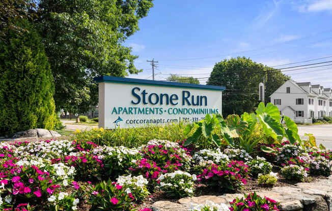 A sign for Stone Run Apartments is surrounded by flowers.