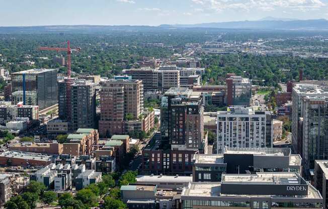 A cityscape with buildings of various heights and a crane in the distance.