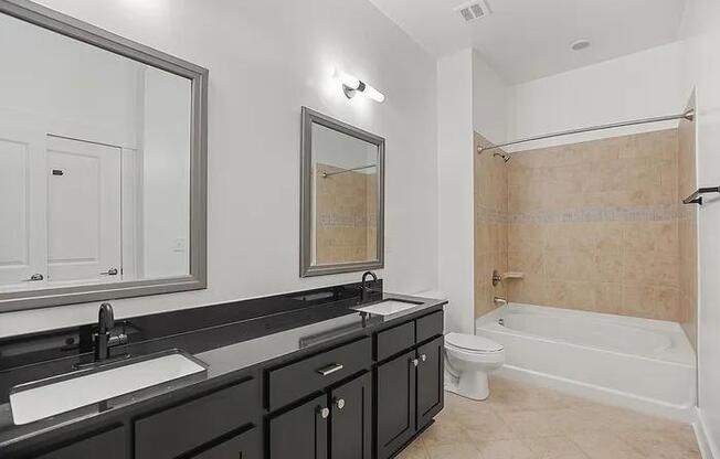 A bathroom with a black vanity and a white bathtub.