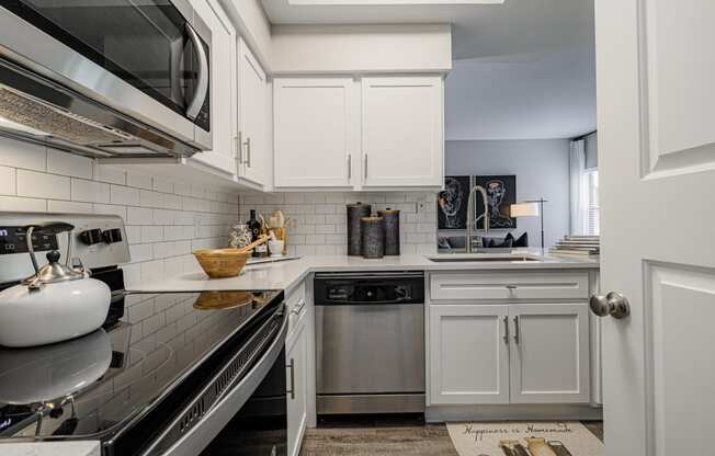 a kitchen with white cabinets and appliances and a black counter top