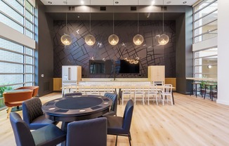 a large room with a round table and chairs and a bar in the background