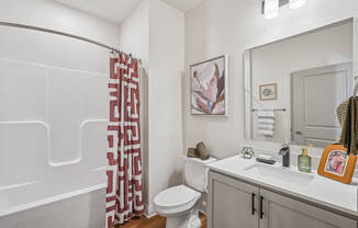 A bathroom with a toilet, sink, and shower curtain.