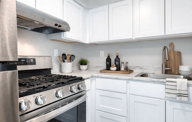 A modern kitchen with a stainless steel stove and white cabinets.