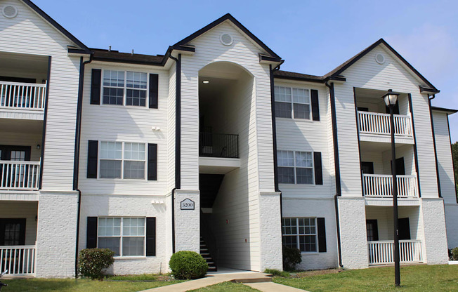 A white apartment building with black shutters and balconies.
