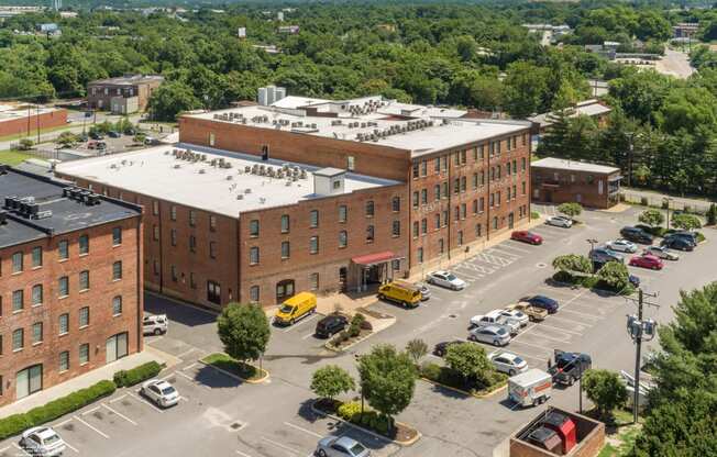 an aerial view of a large brick building with a white roof and a parking lot at Mayton Transfer Lofts, Petersburg, VA