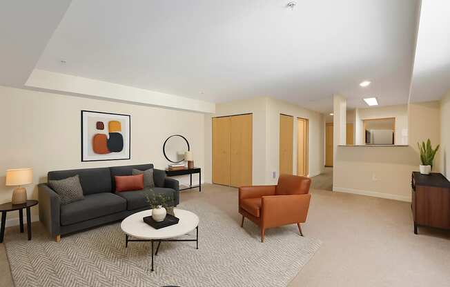A living room with a grey couch, a white coffee table, a round mirror, a lamp, a plant, and a painting on the wall.