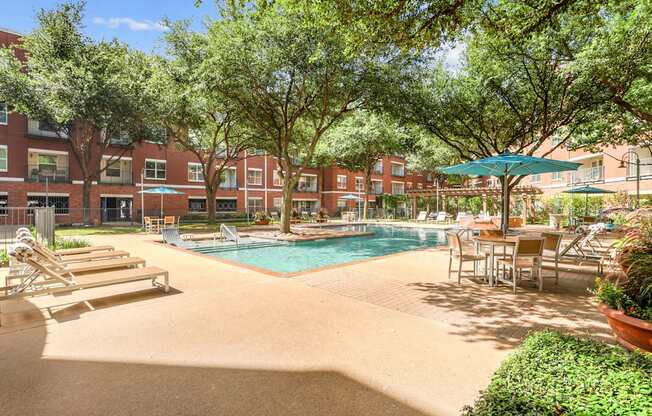 A pool surrounded by trees and chairs.