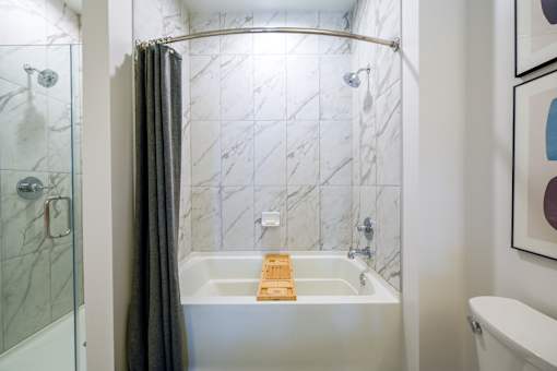 a bathroom with a shower and a bath tub with a wooden tray in it