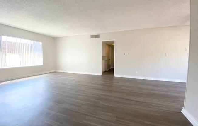 an empty living room with wood floors and a window