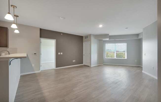 an empty living room and kitchen with wood flooring and a window