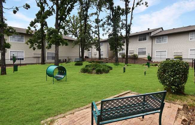 a park bench overlooking a green yard with houses in the background