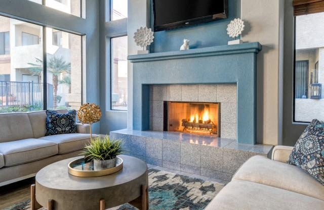 Ingleside Apartments Clubhouse Sitting area with blue fireplace with tv above and beige couches