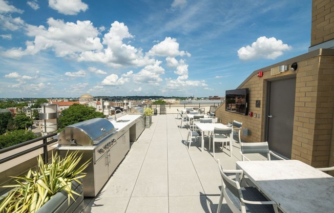 a rooftop patio with tables and chairs and a barbecue grill